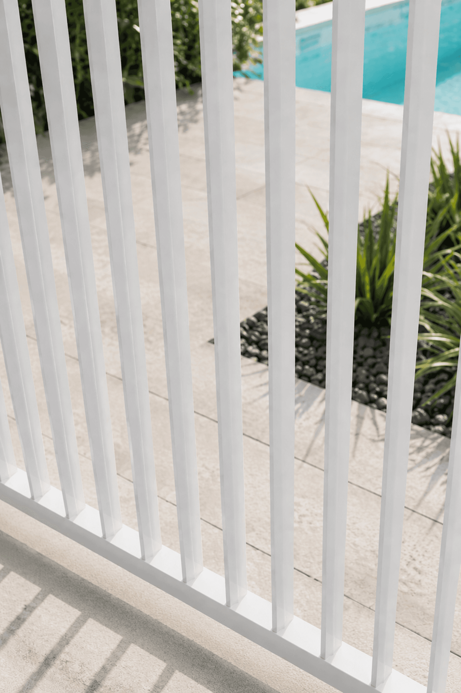 Close-up of white slimline fence balusters by a pool